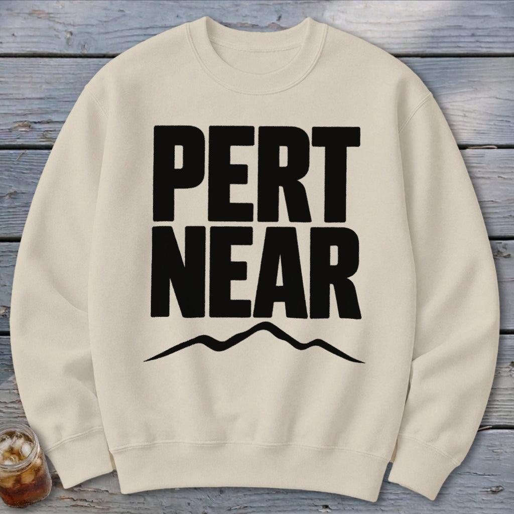 A cream-colored crewneck sweatshirt featuring large black bold text reading PERT NEAR above a mountain outline.