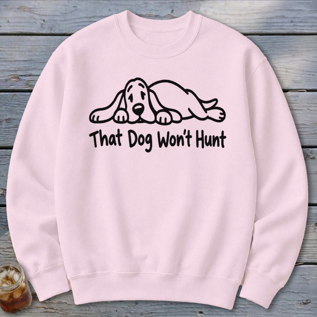 A light pink crewneck sweatshirt featuring a black cartoon hound dog graphic and the text That Dog Won't Hunt.