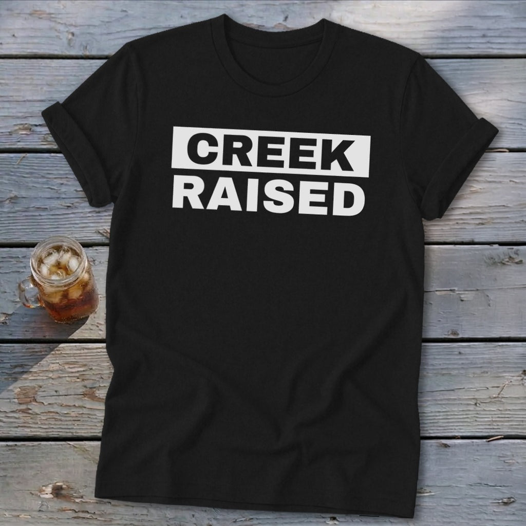 Black t-shirt with white text that reads "CREEK RAISED" and a glass of iced tea.