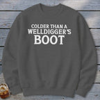 Dark gray crewneck sweatshirt with white text that reads "Colder Than A Welldigger's Boot".